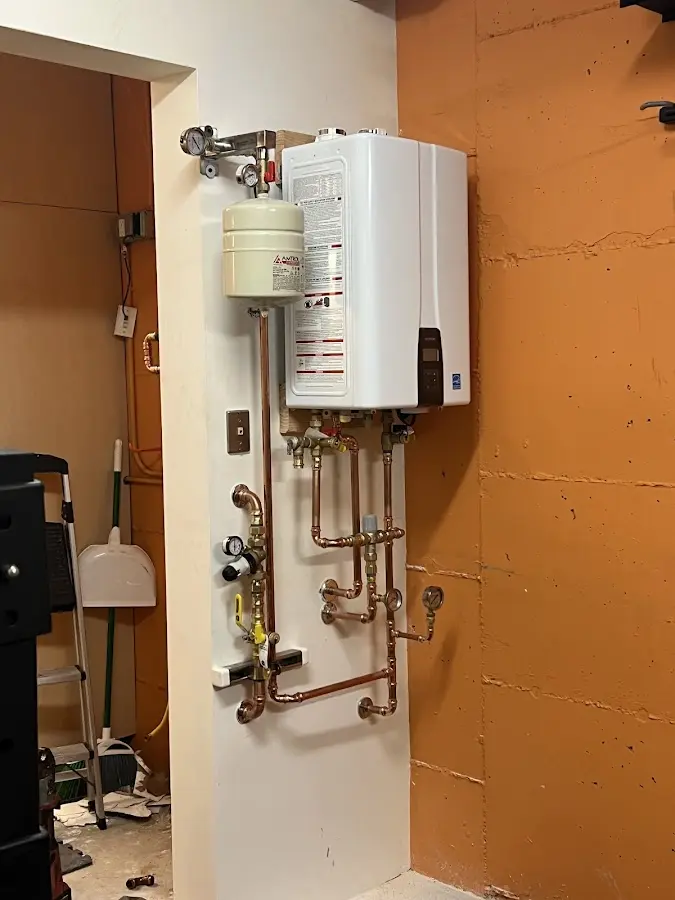 Plumbing technician inspecting water heater connections in Framingham